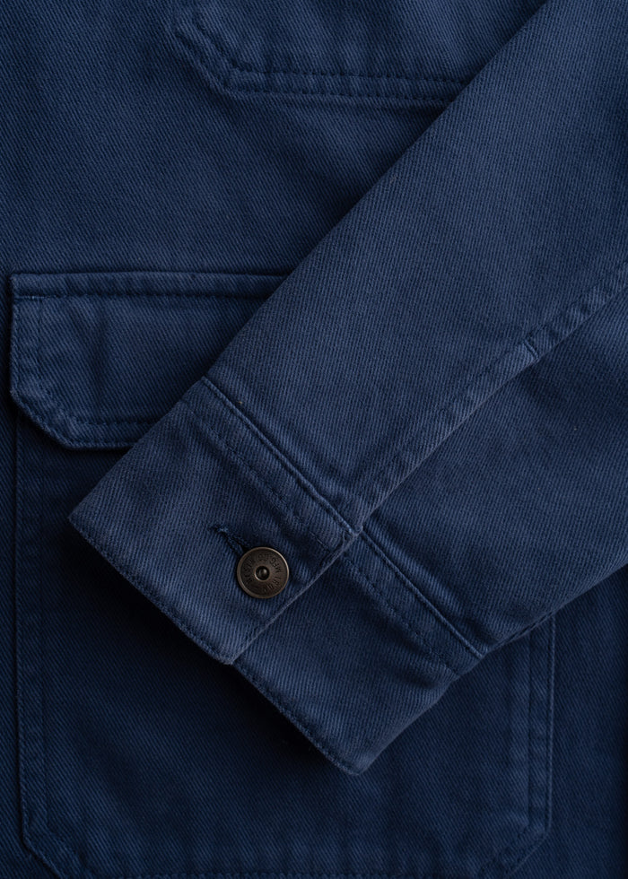 Close-up of a navy blue jacket sleeve with a buttoned cuff and visible pocket stitching, showcasing detailed fabric texture.