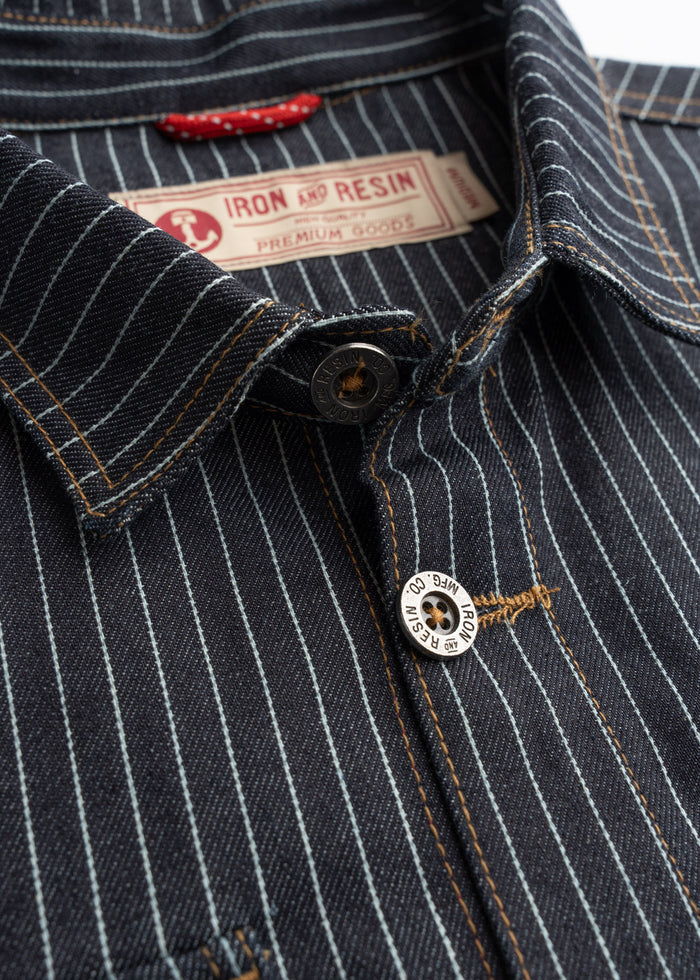 Close up of metal buttons on striped denim shirt, highlighting hardware detail and front closure