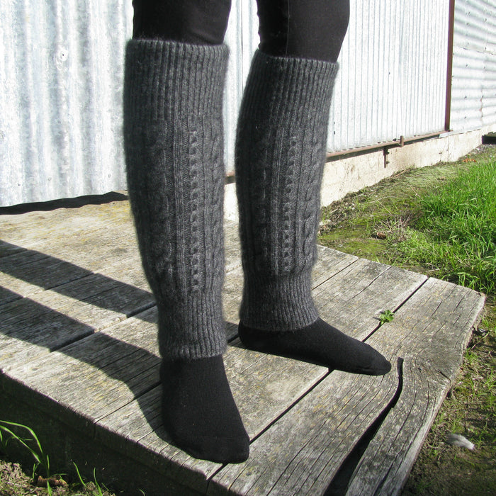 Close up of woman standing wearing grey Koru cable leg warmers.