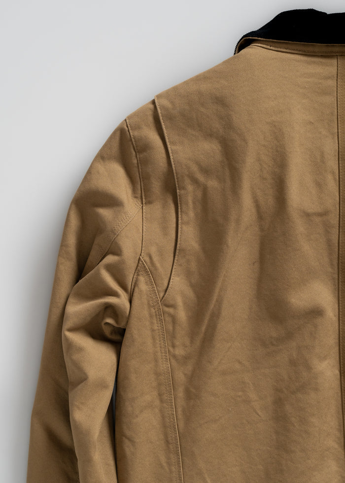 Tan jacket with black collar detail, shown from the back. The fabric appears sturdy, highlighting seams and stitching.