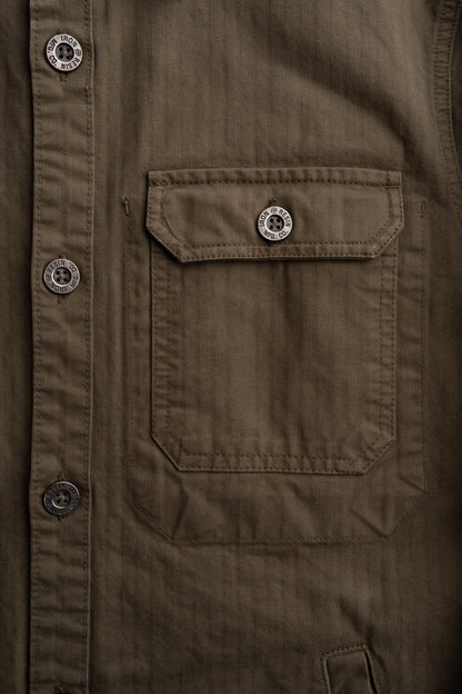 Close-up of a brown jacket with a buttoned flap pocket. Buttons are engraved with "Iron and Resin MFG. CO" for a rugged look.