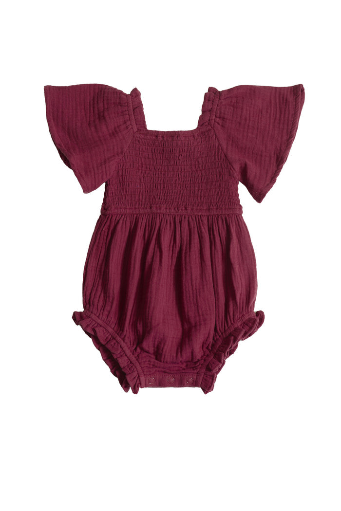 The Ivy City Co Baby Lennon Romper in Wildberry is a maroon cotton romper for babies with short ruffled sleeves, a smocked bodice, and elastic leg openings, shown on a white background.