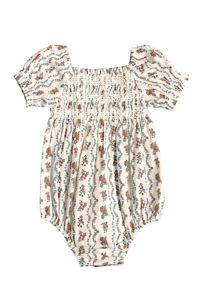 The Ivy City Co Baby Sunday Best Romper in Linear Poppy Woodblock has puffed short sleeves, a smocked bodice, and gathered legs. Cream fabric with red, blue, and green poppy print. Laid flat on white. Ideal for Mom and Me matching looks.