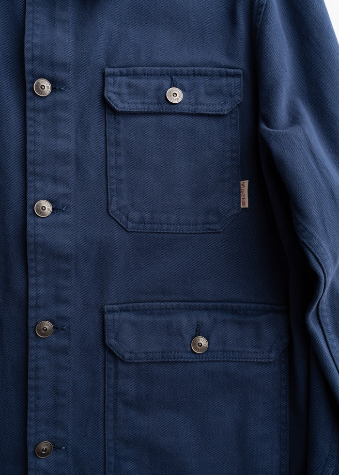 Close up of front pocket layout on denim jacket, showcasing three pocket storage and stitching detail