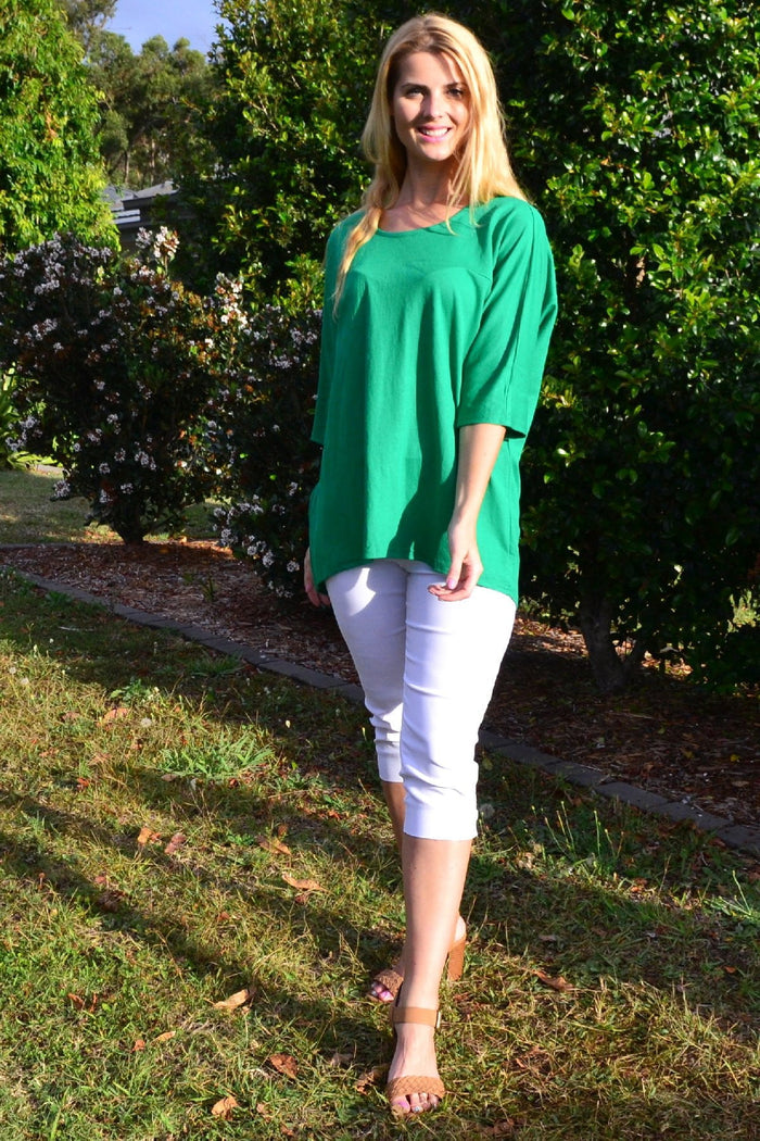 Grass green Stylius sloping sleeve tunic top with a relaxed fit and flowing silhouette, displayed on a hanger.