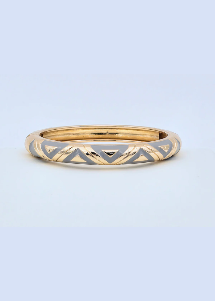 Gold and grey geometric pattern bangle bracelet on a blue background