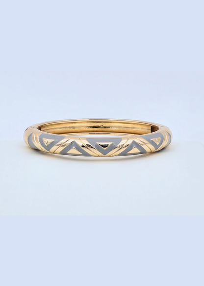 Gold and grey geometric pattern bangle bracelet on a blue background