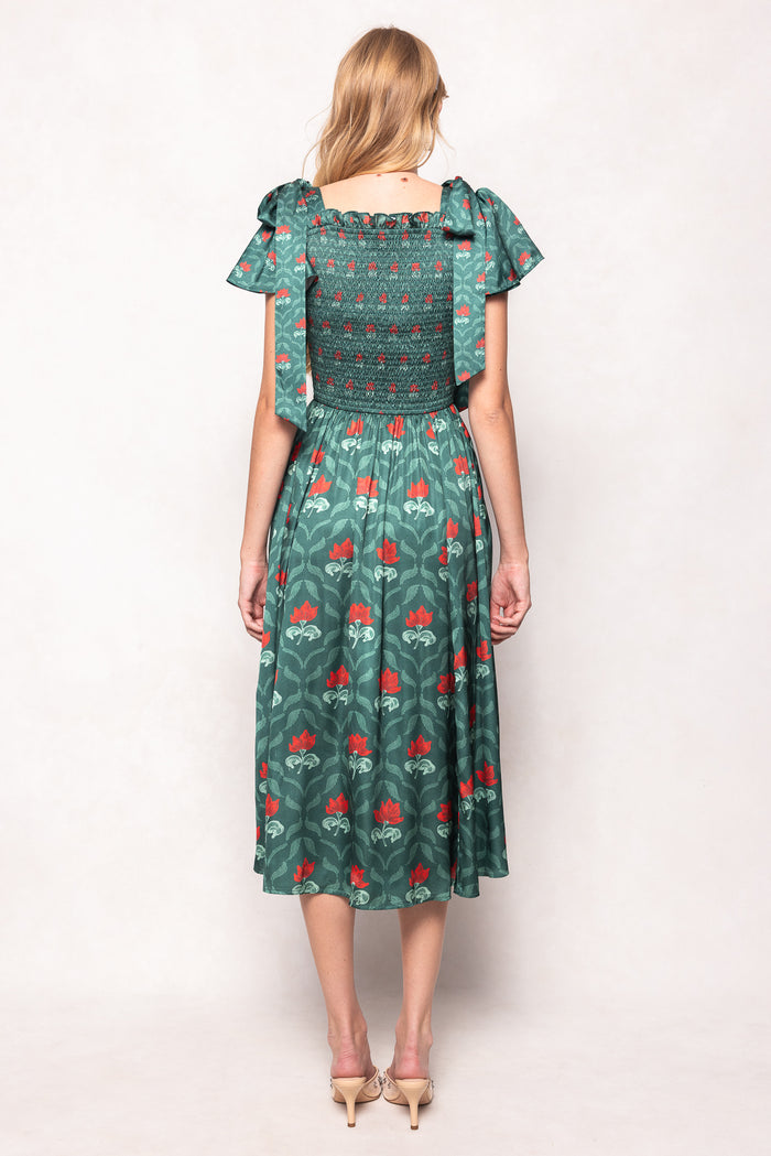 Woman wearing a green floral dress with a plain background