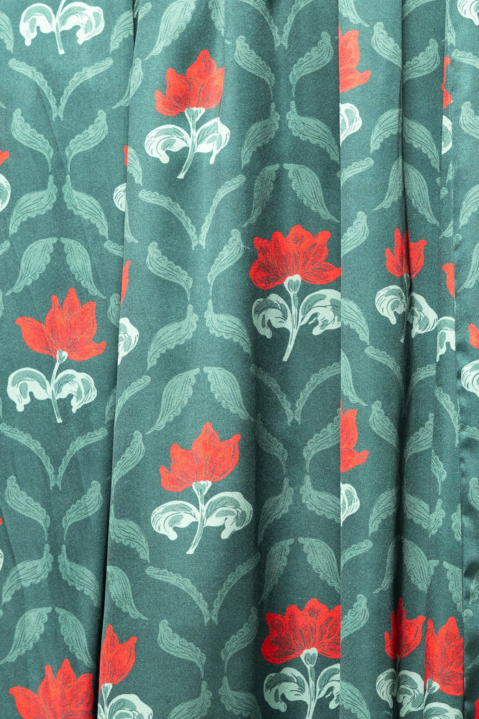 The Rayna Dress in Green Floral Block by Ivy City Co features a vintage-inspired botanical print with red flowers and white leaves arranged in vertical rows. Designed with nursing-friendly functionality for added convenience.