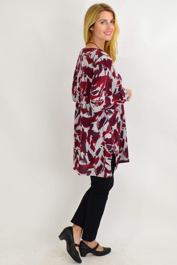 Red and grey paint splash fleece tunic top by Hourglass, featuring a relaxed fit and artistic design, displayed on a hanger.