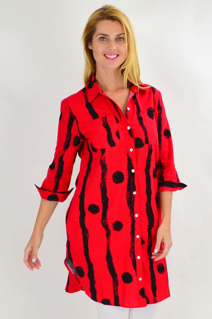 Red Ruby Rain tunic shirt with black polka dots, long sleeves and relaxed fit, displayed on a hanger.