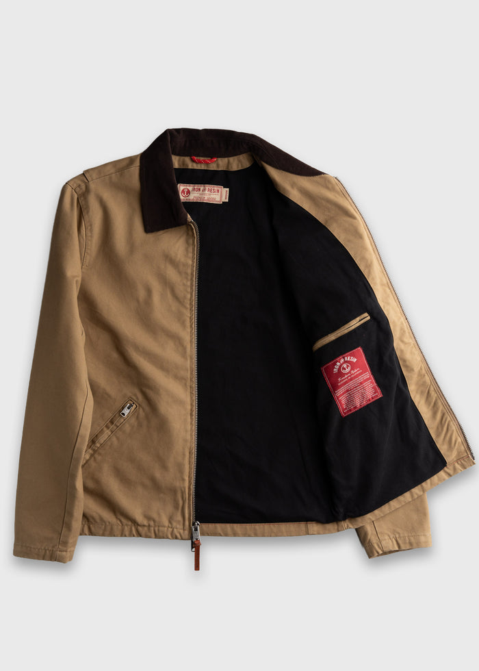 Tan jacket with dark collar, open to show black lining and red label inside. Zippered front and pocket detail visible.