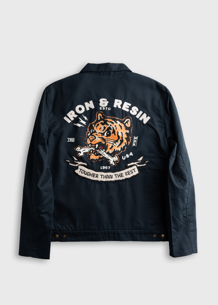 Navy jacket back with a fierce tiger design, "Iron & Resin," and "Tougher Than The Rest" text in bold white and orange.