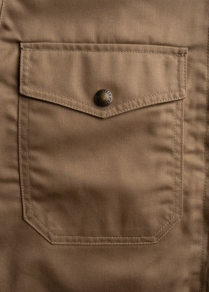 Close-up of a brown fabric pocket with a metal button, showcasing detailed stitching and texture.